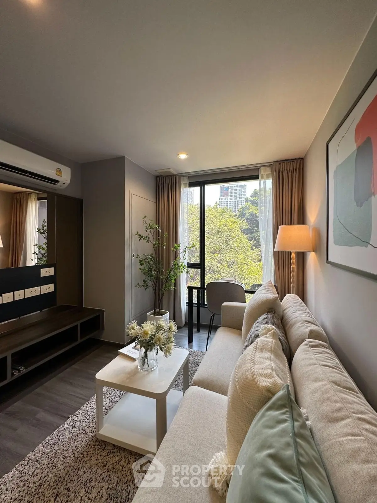 Modern living room with large window and stylish decor, offering a serene view of greenery.