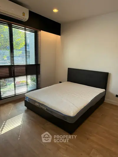 Spacious bedroom with large window and modern design in a serene setting.