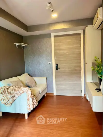 Cozy living room with modern decor and wooden flooring, featuring a comfortable sofa and stylish lighting.