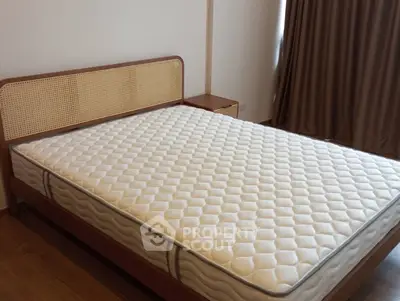 Spacious bedroom with elegant wooden bed frame and comfortable mattress.