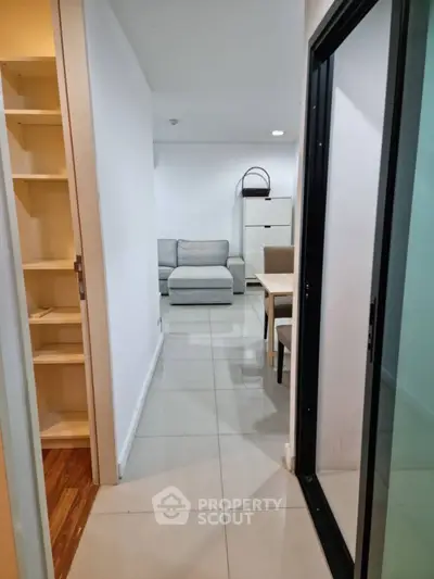 Modern apartment hallway leading to cozy living room with sleek furniture
