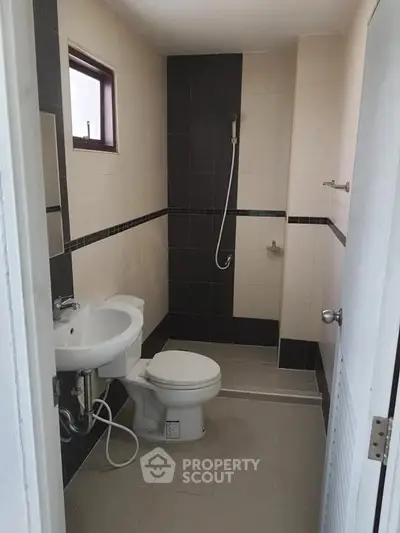 Compact bathroom with modern fixtures and neutral tile design, ideal for efficient space utilization.