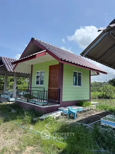 Charming small green house with a red roof in a serene rural setting, perfect for a peaceful retreat.