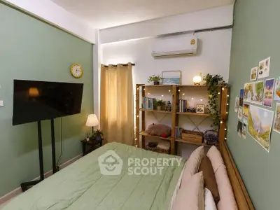 Cozy bedroom with green walls, wall-mounted TV, and decorative shelving.
