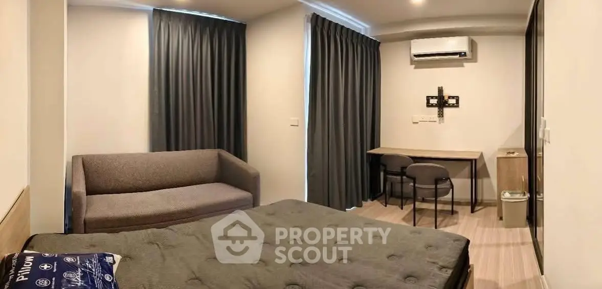 Modern bedroom with cozy sofa and study desk, featuring elegant curtains and air conditioning.