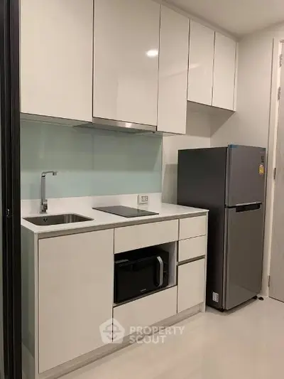 Modern compact kitchen with sleek white cabinets and stainless steel appliances