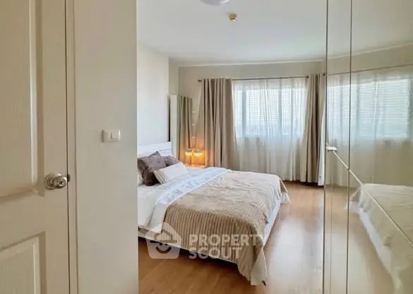 Spacious bedroom with large windows and mirrored closet doors, offering ample natural light and modern decor.