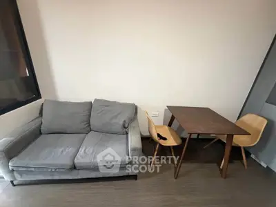 Cozy living room with a gray sofa and wooden dining table set, perfect for modern apartment living.