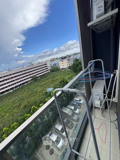 High-rise balcony with scenic view of cityscape and greenery, featuring clothes drying rack.