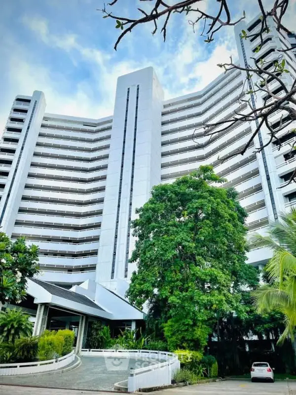 Stunning modern high-rise building with lush greenery and clear blue sky.