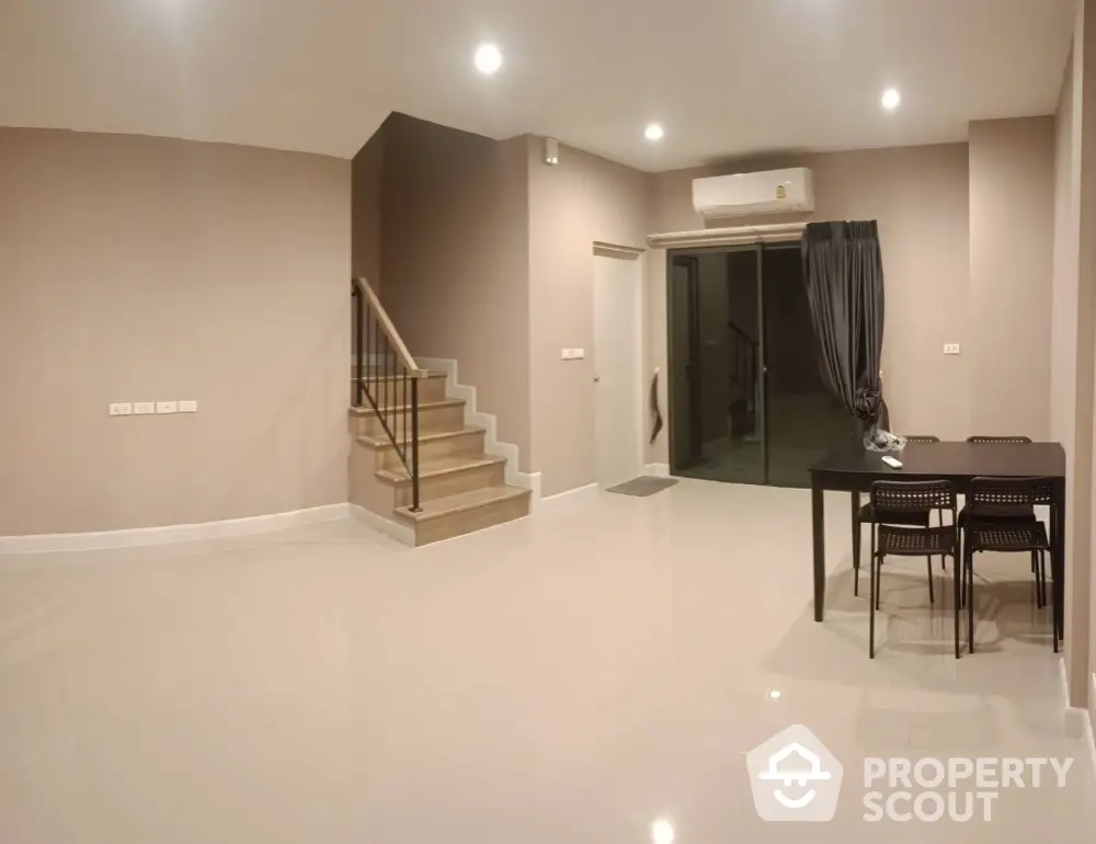 Spacious and modern living area with glossy tiled floors, elegant staircase, and ample lighting, perfect for family gatherings and entertainment.