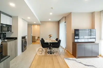 Modern open-plan living room with dining area and kitchen featuring sleek appliances.