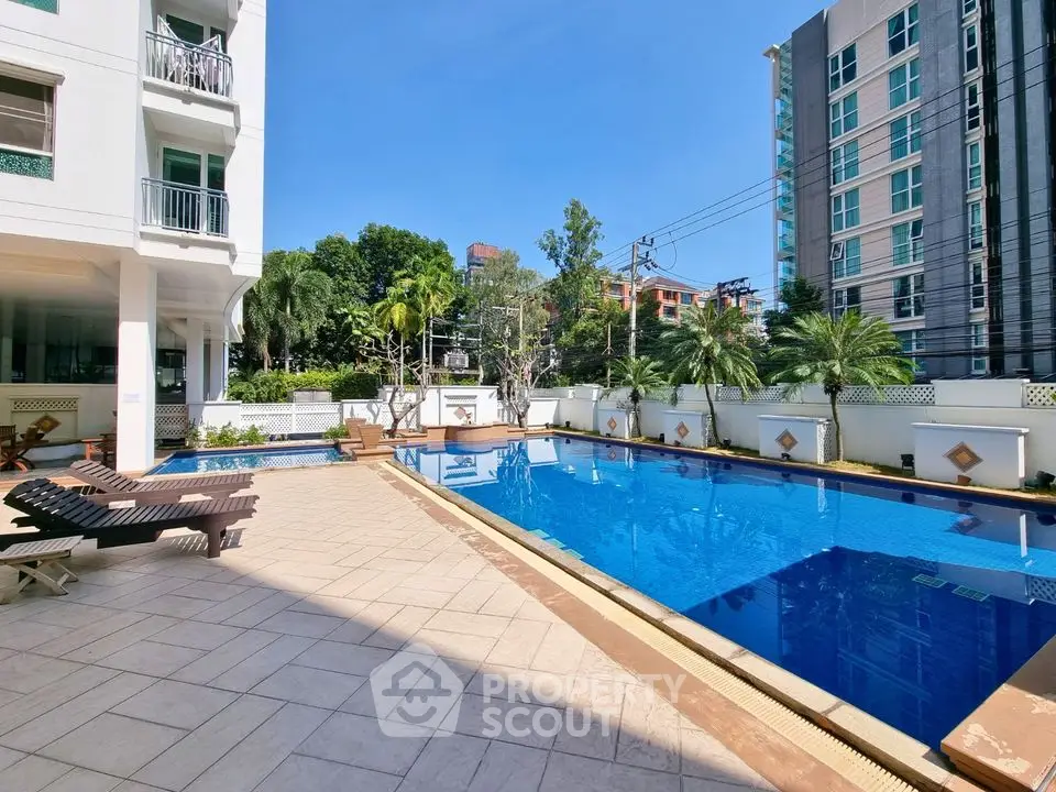 Luxurious apartment complex with stunning outdoor pool and sunbathing area.
