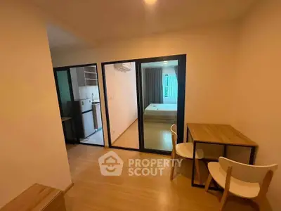 Modern apartment interior with open layout, featuring a cozy dining area and view into bedroom and kitchen.