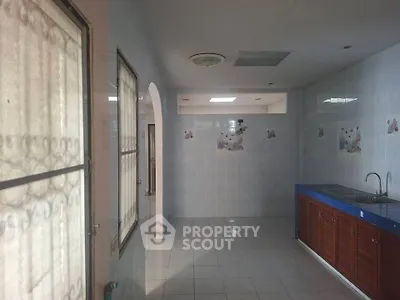 Spacious kitchen with tiled walls and wooden cabinets, featuring a large window for natural light.