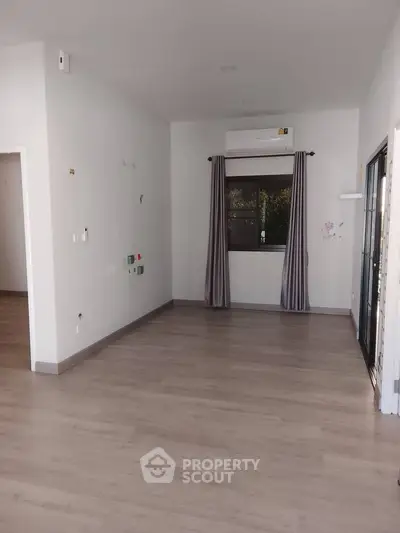 Spacious empty room with wooden flooring and air conditioning