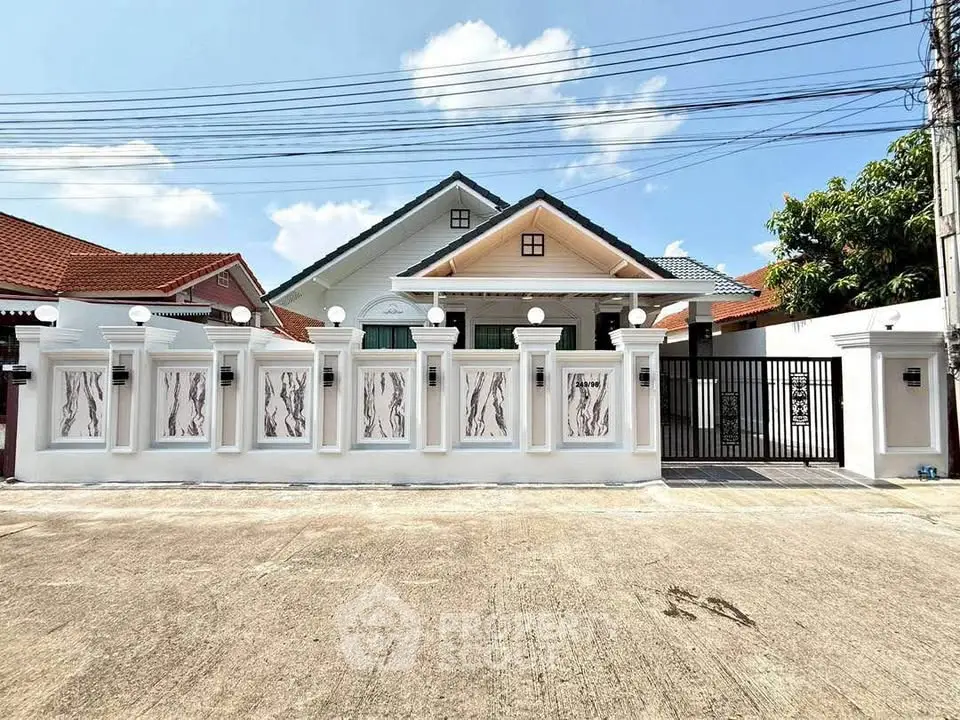 Charming suburban house with elegant white fence and spacious driveway under clear blue sky.