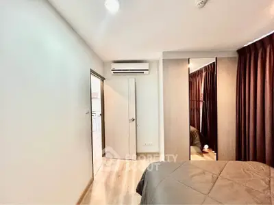 Modern bedroom with air conditioning and wooden flooring, featuring a cozy bed and stylish curtains.