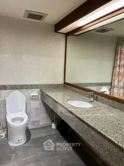 Spacious bathroom with granite countertop and large mirror in modern home.