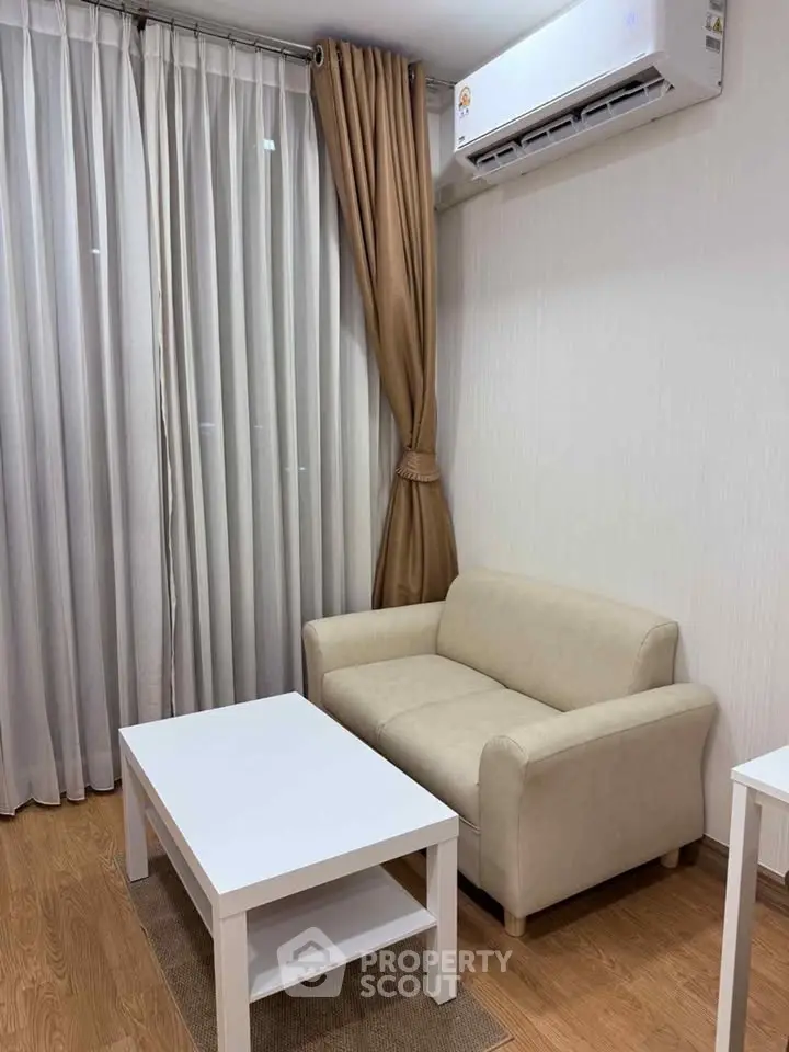 Cozy living room with beige sofa, white coffee table, and elegant curtains under air conditioning.