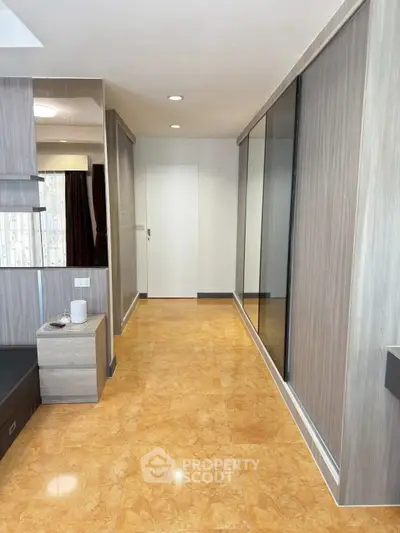 Modern bedroom with sleek wooden paneling and mirrored wardrobe doors