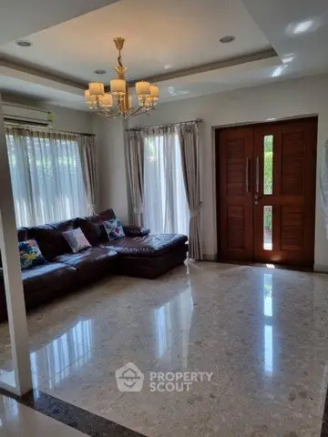 Spacious living room with elegant chandelier and large windows for natural light.