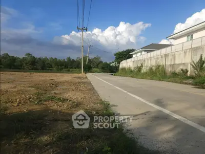 Scenic suburban road with adjacent empty plot and residential wall