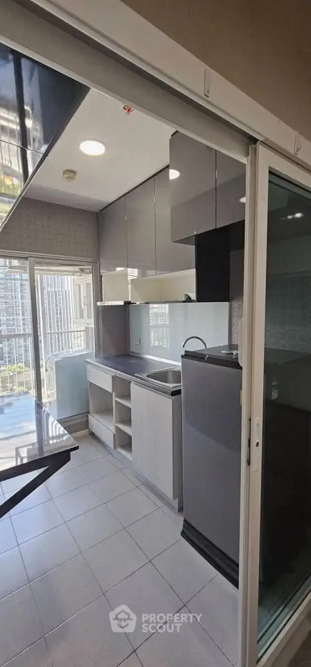 Modern kitchen with sleek cabinets and large windows offering natural light and city views.