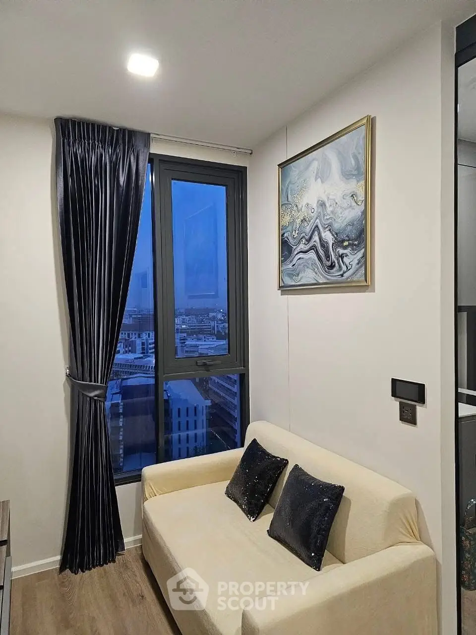 Cozy living room with city view, elegant decor, and modern furnishings in a high-rise apartment.