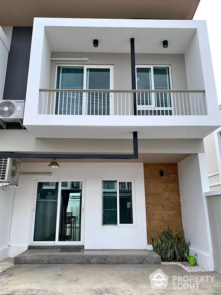 Modern two-story townhouse with sleek balcony and contemporary facade, featuring large windows and minimalistic design.