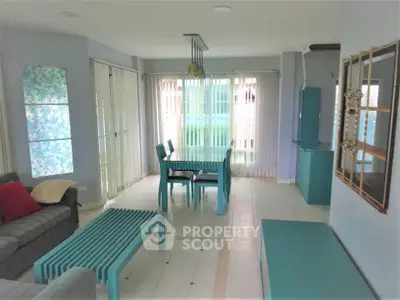 Spacious living room with modern teal furniture and large windows for natural light.