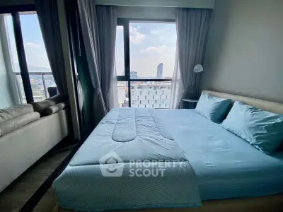 Modern bedroom with large windows offering stunning city views and cozy furnishings.