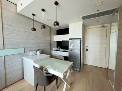 Modern kitchen with sleek design, featuring a dining area and stainless steel appliances in a stylish apartment.