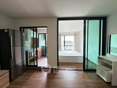 Modern apartment interior with open layout, featuring kitchen, bedroom, and living area with large windows.
