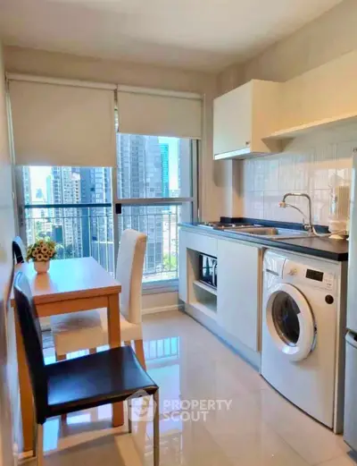Modern kitchen with city view, featuring washing machine and dining area, ideal for urban living.