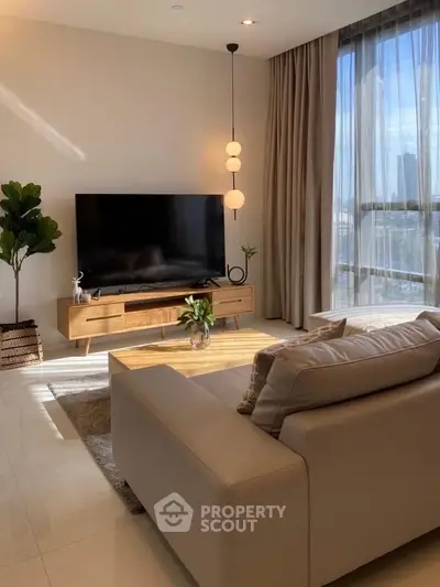 Modern living room with large TV, stylish furniture, and floor-to-ceiling windows offering city views.