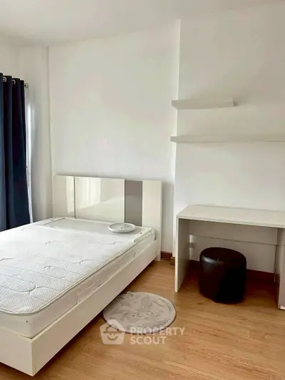 Minimalist bedroom with white furniture and wooden flooring