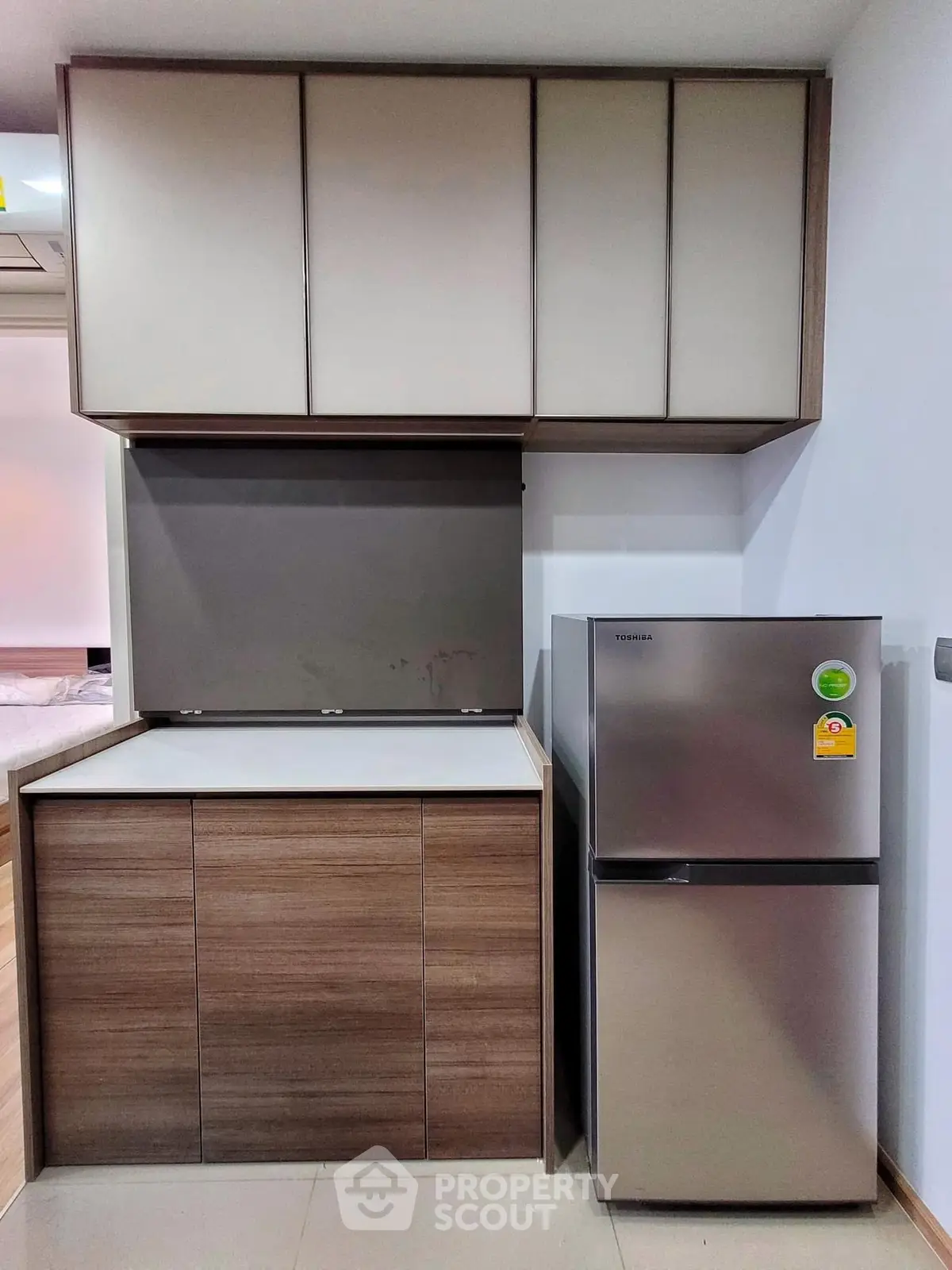 Modern kitchen with sleek cabinetry and stainless steel fridge in compact layout.
