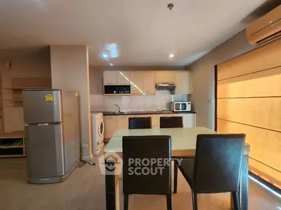 Modern kitchen with dining area, featuring fridge, washing machine, and microwave in open layout.