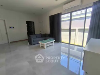 Spacious living room with modern sofa and large windows offering ample natural light.