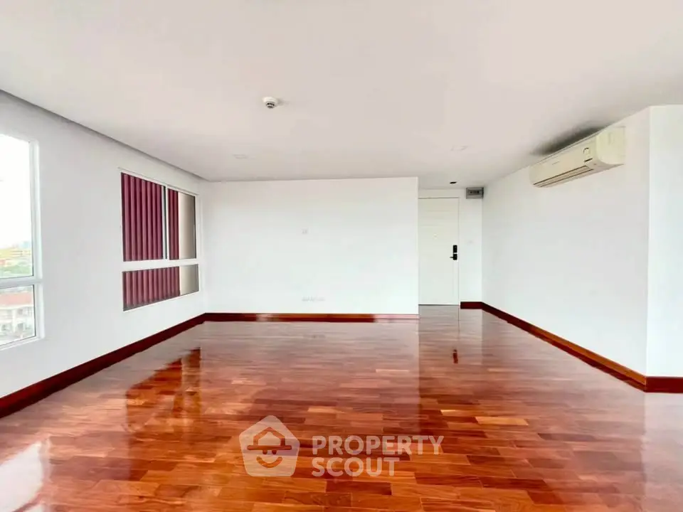 Spacious living room with polished wooden floors and natural light.