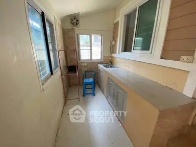 Compact kitchen area with tiled countertop and windows for natural light