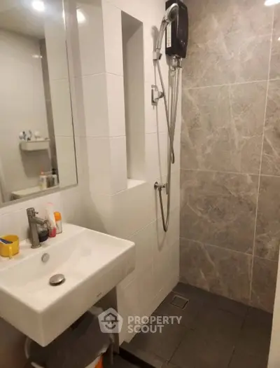 Modern bathroom with sleek sink and shower in stylish tiled setting.