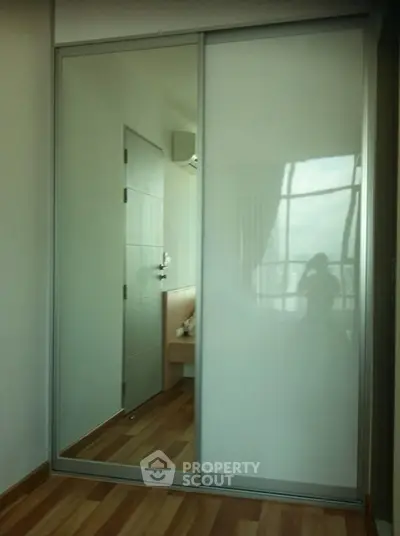 Modern bedroom with mirrored sliding closet doors and wooden flooring.