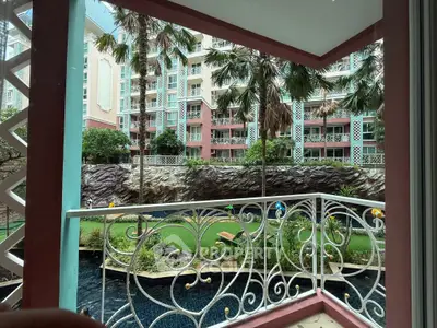 Charming balcony view overlooking lush garden and modern building facade.