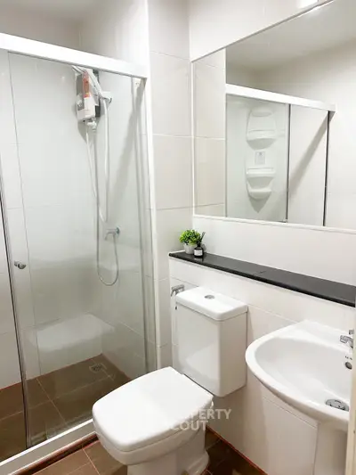 Modern bathroom with glass shower enclosure and sleek fixtures in a contemporary apartment.
