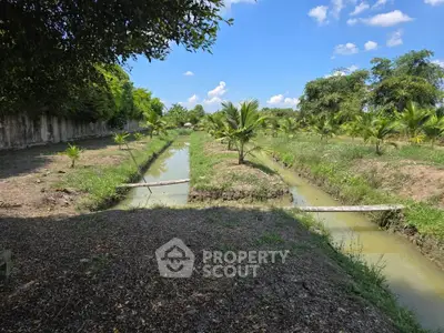 Scenic view of lush green garden with small water canals under a bright blue sky.