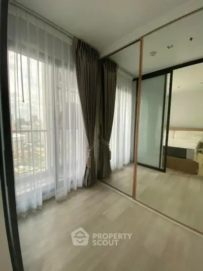 Spacious bedroom with mirrored closet and large windows offering natural light
