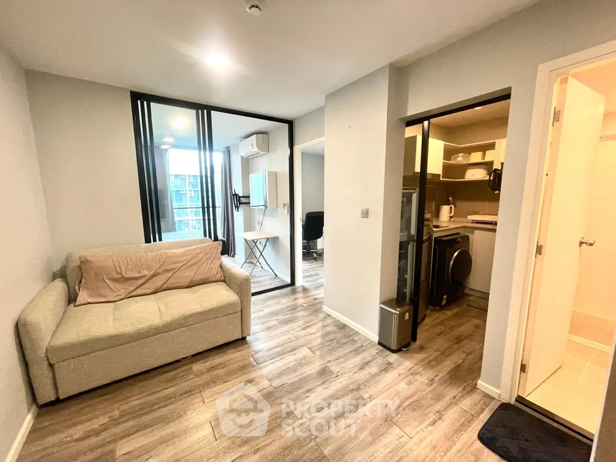 Modern apartment interior with cozy living room and compact kitchen, featuring stylish decor and wooden flooring.