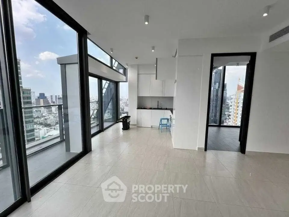 Spacious modern apartment with floor-to-ceiling windows and city views, featuring an open kitchen layout.